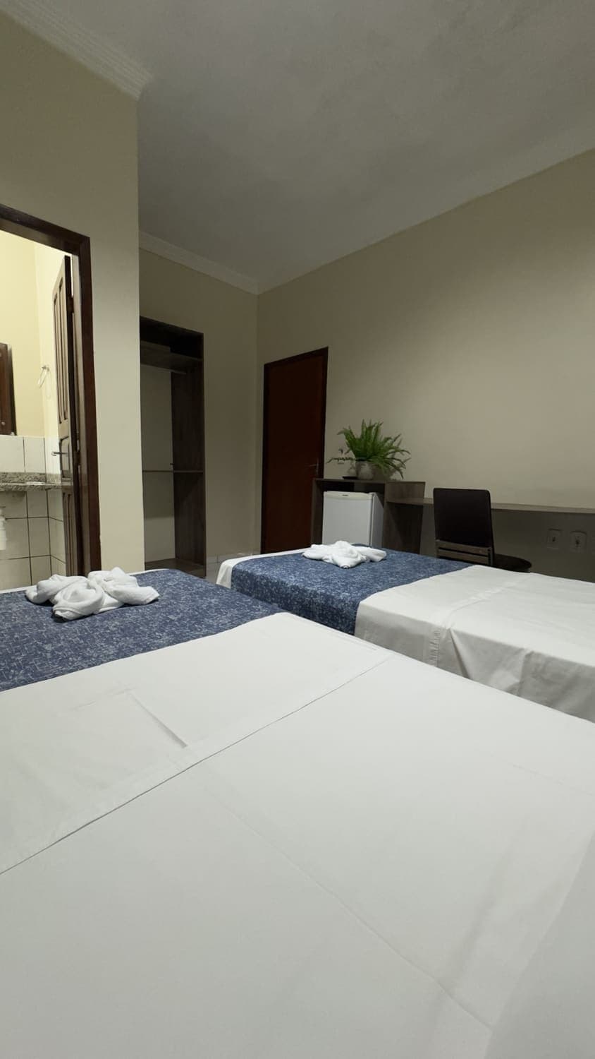 Quarto com camas de solteiro, frigobar e banheiro privativo